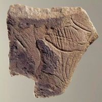 Plaquette calcaire figurant un profil de visage tourné vers la droite, mi-humain, mi-félin, les joues striées symbolisant peut-être un tatouage ou des scarifications,  découverte dans la grotte de la Marche (Vienne). Epoque magdalénienne (12 000 à 14 000 ans)