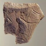 Plaquette calcaire figurant un profil de visage tourné vers la droite, mi-humain, mi-félin, les joues striées symbolisant peut-être un tatouage ou des scarifications,  découverte dans la grotte de la Marche (Vienne). Epoque magdalénienne (12 000 à 14 000 ans)